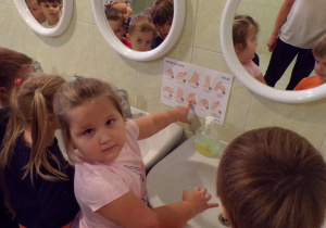 Dziewczynka wskazująca na instrukcję mycia rąk