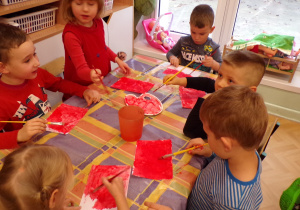 Dzieci malujące karton na czerwono