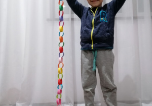Chłopiec prezentujący papierowy łańcuch