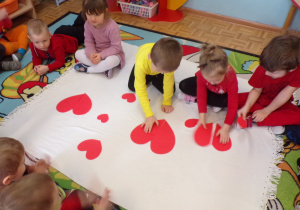 Dzieci składające papierowe połówki serc