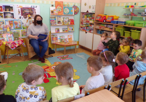 Dzieci słuchające bajki czytanej przez panią bibliotekarz